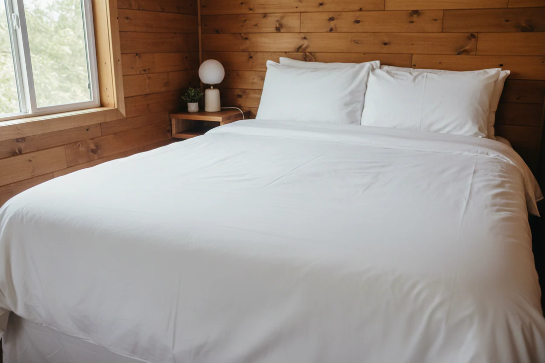 Crisp white hotel-quality bedding on a bed in a cozy cabin STR property — the premium sleep standard for short-term rental hosts