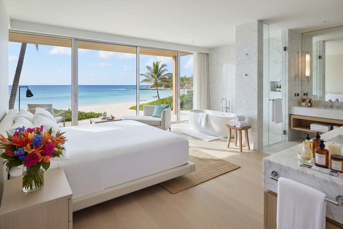 Luxury beachfront resort suite with crisp white hotel-quality bedding, freestanding tub, and premium bath amenities — the standard for luxury