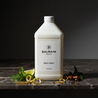 Balmain Paris Body Wash gallon refill — retail bottle on dark marble bathroom vanity shelf, soft warm spa lighting